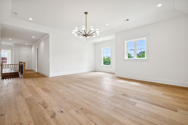 unfurnished room featuring a notable chandelier and light hardwood / wood-style flooring