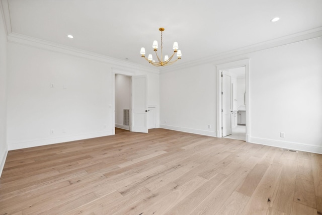 empty room with a notable chandelier, ornamental molding, and light hardwood / wood-style flooring