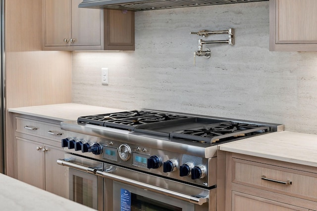 kitchen with double oven range, light brown cabinetry, and tasteful backsplash