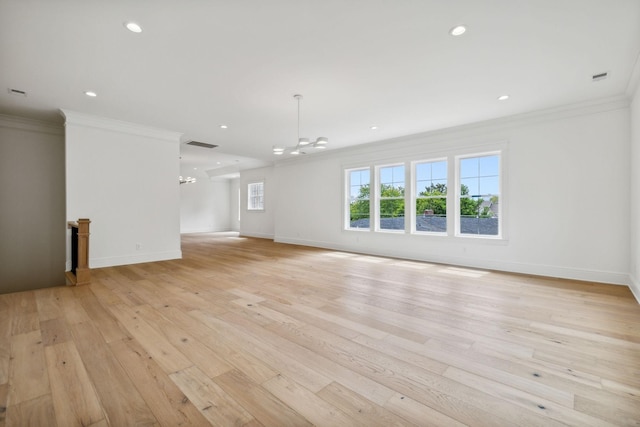 unfurnished living room featuring an inviting chandelier, light wood-type flooring, and crown molding