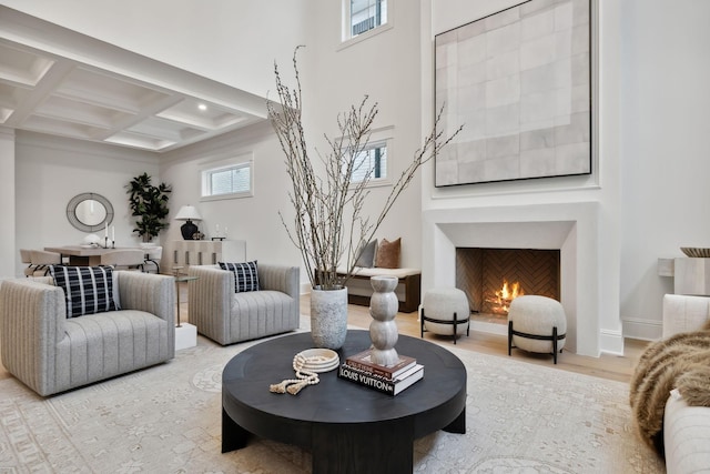 living room featuring coffered ceiling, light hardwood / wood-style flooring, and beamed ceiling