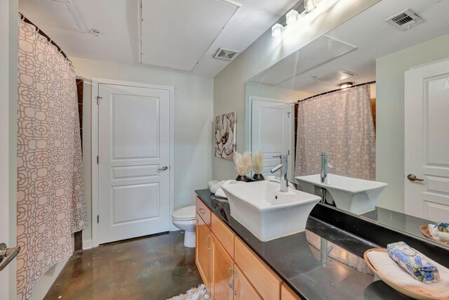 bathroom featuring toilet, concrete floors, and vanity