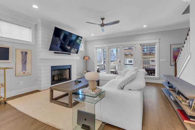 living room with a fireplace, hardwood / wood-style floors, ceiling fan, and crown molding