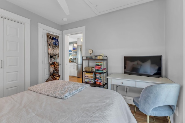 bedroom with stainless steel fridge and wood-type flooring