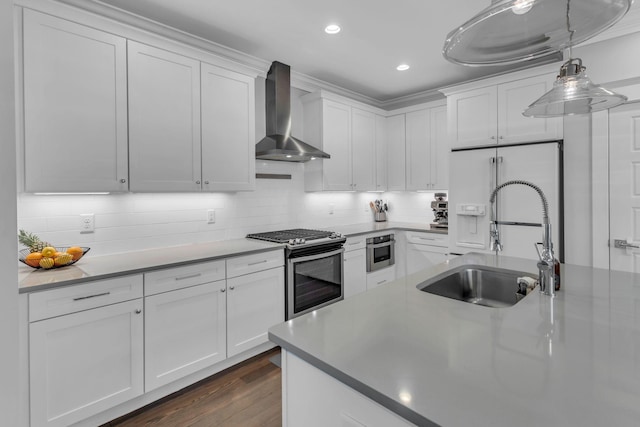 kitchen featuring white cabinets, stainless steel appliances, sink, and wall chimney exhaust hood