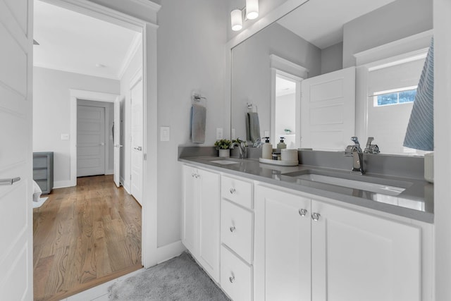 bathroom featuring wood-type flooring, vanity, and ornamental molding