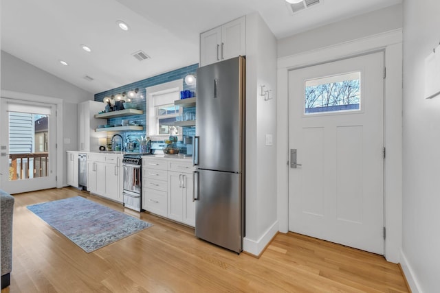 kitchen with stainless steel appliances, vaulted ceiling, decorative backsplash, and white cabinetry