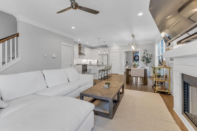 living room featuring hardwood / wood-style floors, ceiling fan, and crown molding