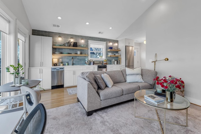 living room with lofted ceiling, light hardwood / wood-style floors, and sink