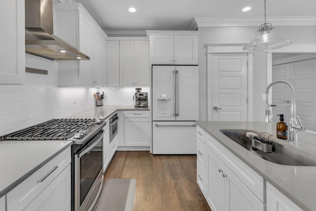 kitchen with stainless steel appliances, white cabinets, decorative light fixtures, wall chimney exhaust hood, and backsplash