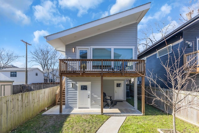 back of house with a deck, a patio area, and a yard