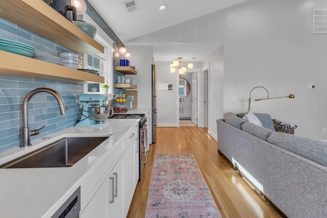 kitchen with vaulted ceiling, light hardwood / wood-style floors, decorative backsplash, white cabinets, and sink