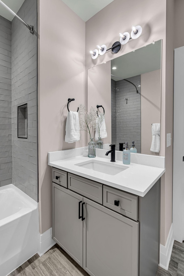 bathroom with tiled shower / bath combo, vanity, and wood-type flooring