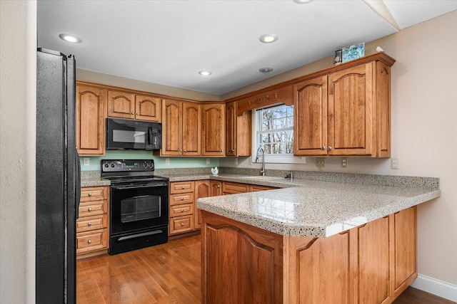 kitchen featuring kitchen peninsula, dark hardwood / wood-style floors, black appliances, and sink