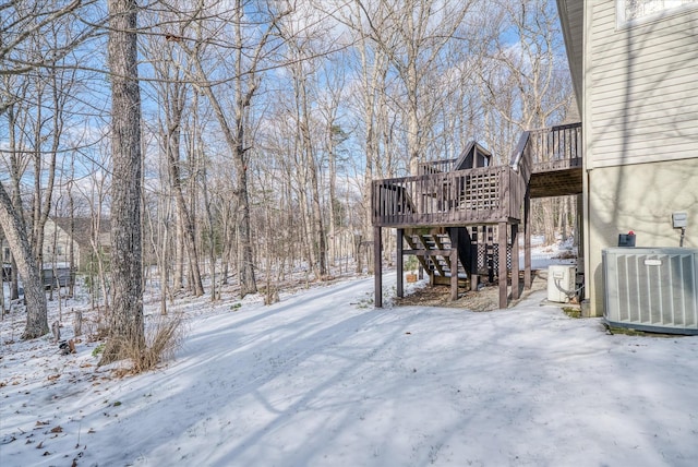 snowy yard with central AC unit and a wooden deck