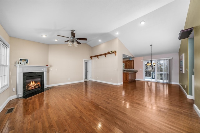 unfurnished living room with ceiling fan with notable chandelier, a high end fireplace, vaulted ceiling, and hardwood / wood-style floors