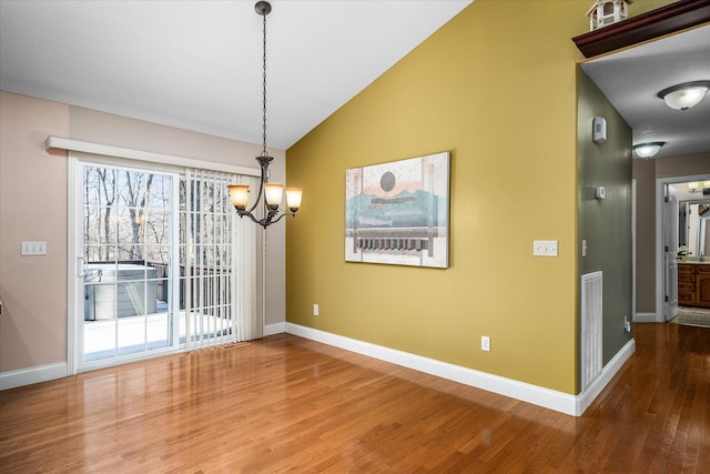 unfurnished dining area featuring hardwood / wood-style flooring, vaulted ceiling, and a chandelier