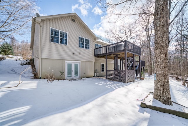 snow covered house featuring french doors and a wooden deck