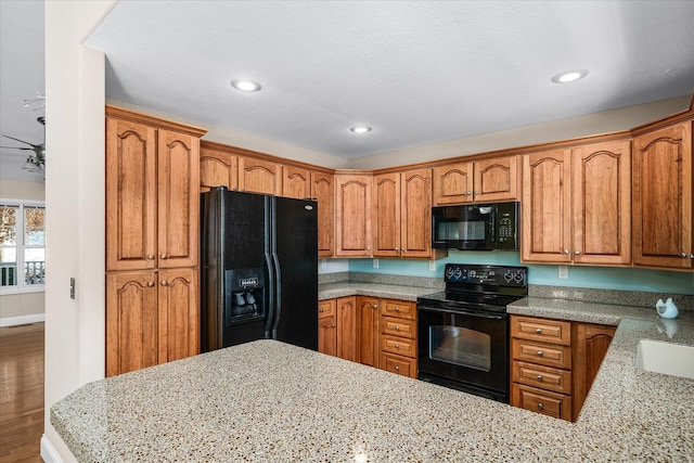 kitchen with sink, ceiling fan, black appliances, and light stone counters