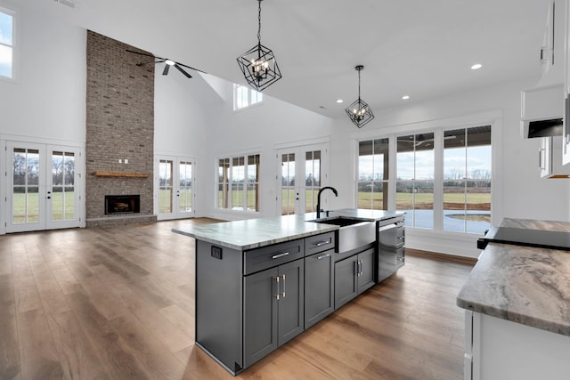 kitchen featuring sink, pendant lighting, french doors, and an island with sink