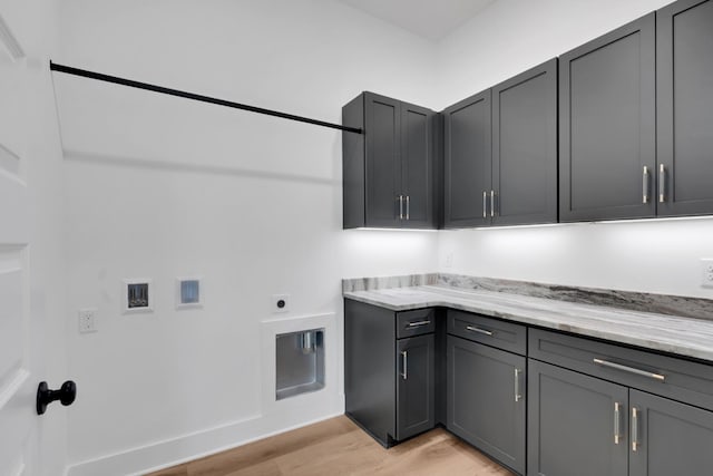 clothes washing area with light wood-type flooring, cabinets, and hookup for an electric dryer