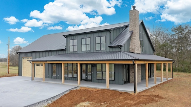 rear view of property with a porch and a garage