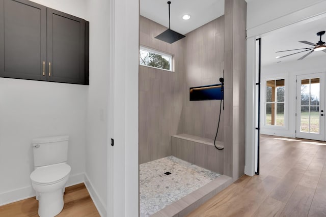 bathroom featuring toilet, a tile shower, ceiling fan, and plenty of natural light