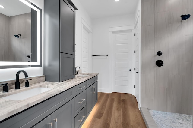 bathroom with vanity, hardwood / wood-style flooring, and tiled shower