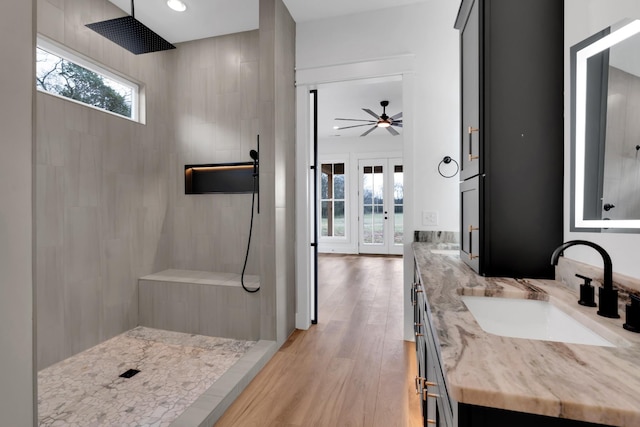 bathroom featuring a tile shower, french doors, ceiling fan, wood-type flooring, and vanity