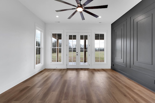 unfurnished room with ceiling fan, a wealth of natural light, and wood-type flooring