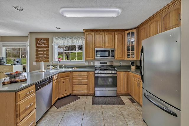 kitchen featuring stainless steel appliances, a textured ceiling, light tile patterned floors, and sink