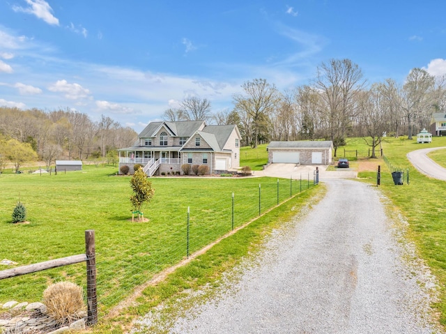 view of front of home featuring a porch, a rural view, an outbuilding, a garage, and a front yard