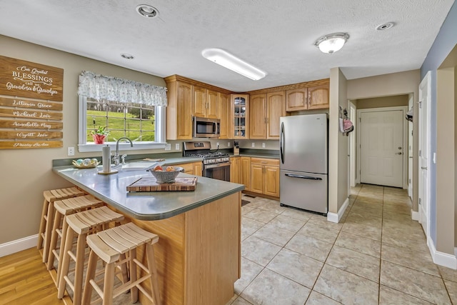 kitchen featuring stainless steel appliances, sink, a textured ceiling, light tile patterned floors, and kitchen peninsula