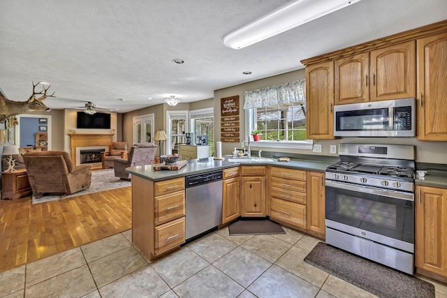 kitchen with sink, ceiling fan, light tile patterned floors, kitchen peninsula, and appliances with stainless steel finishes