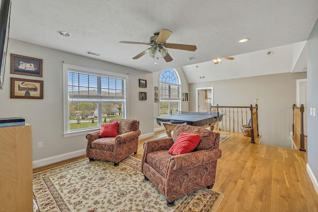 recreation room with lofted ceiling, a textured ceiling, and light hardwood / wood-style floors