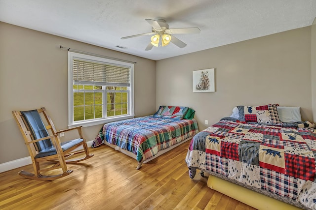 bedroom featuring ceiling fan, light hardwood / wood-style flooring, and a textured ceiling