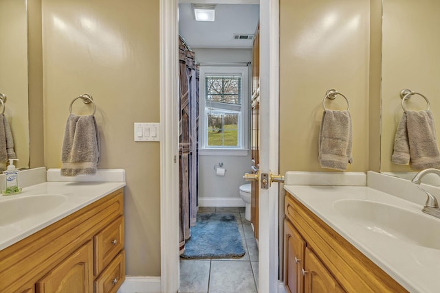 bathroom with toilet, vanity, and tile patterned floors