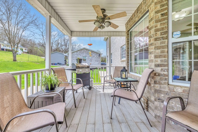 wooden terrace featuring ceiling fan, area for grilling, and a lawn