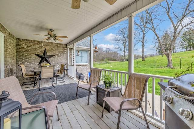 wooden deck featuring ceiling fan, a yard, and a grill