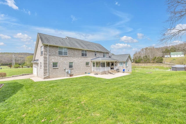 rear view of house with a yard, a garage, and a patio area