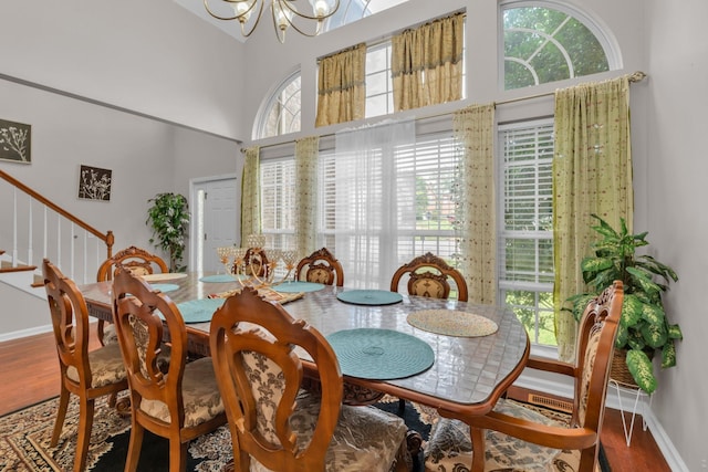 dining area with a high ceiling, hardwood / wood-style flooring, and an inviting chandelier