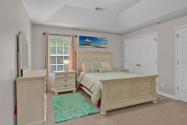 carpeted bedroom with a closet and a tray ceiling