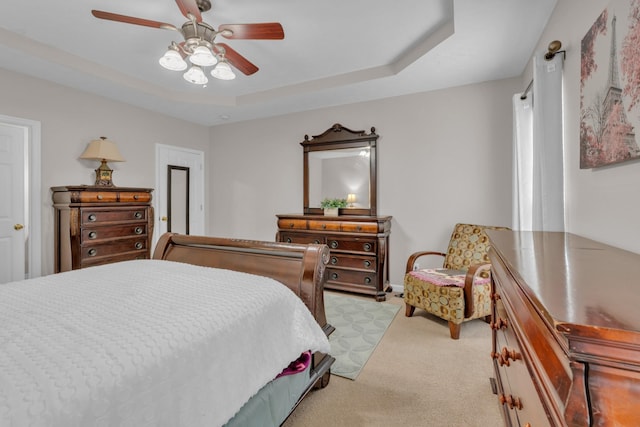 carpeted bedroom featuring ceiling fan and a tray ceiling