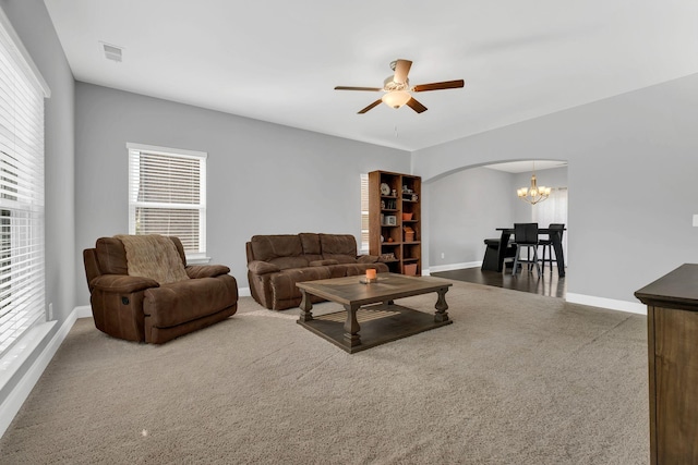 carpeted living room with ceiling fan with notable chandelier and plenty of natural light