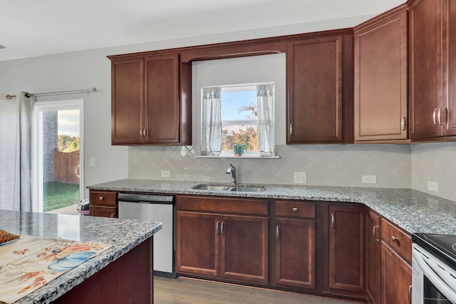 kitchen with light stone counters, stainless steel appliances, light hardwood / wood-style floors, tasteful backsplash, and sink