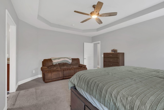 carpeted bedroom with ceiling fan and a tray ceiling