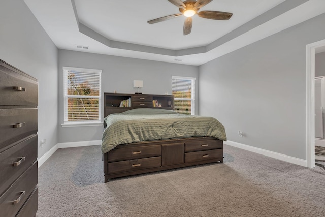 carpeted bedroom with ceiling fan and a raised ceiling