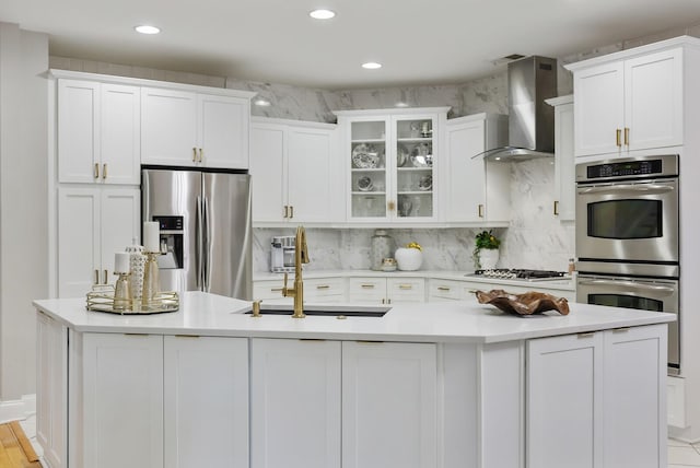 kitchen featuring stainless steel appliances, sink, white cabinetry, wall chimney exhaust hood, and decorative backsplash