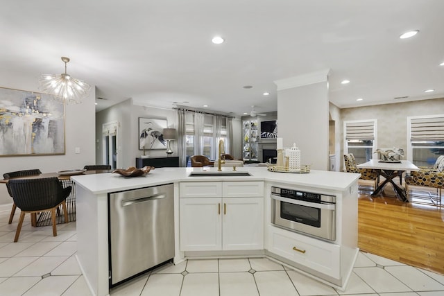 kitchen featuring pendant lighting, stainless steel appliances, a notable chandelier, white cabinetry, and sink