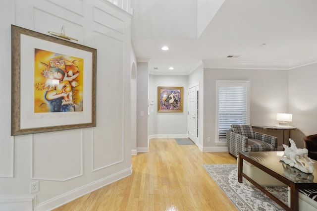 hall with light wood-type flooring and crown molding